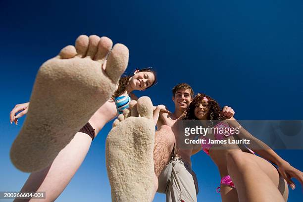 teenagers (14-17), two holding up sandy feet, portrait, view from below - young teen girl beach foto e immagini stock
