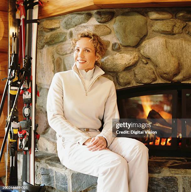woman sitting by fireside, smiling, portrait - ski pants stockfoto's en -beelden
