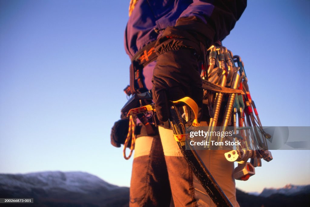 Female mountaineer carrying winter climbing equipment, mid section
