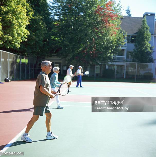 senior couple playing tennis, side view - doubles sports stock pictures, royalty-free photos & images