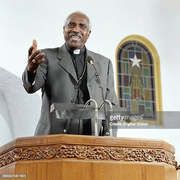 senior priest giving sermon, smiling, low angle view - senior pastor stockfoto's en -beelden