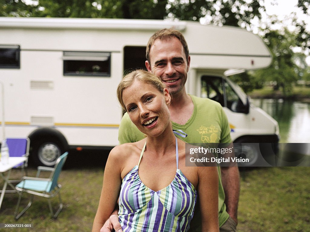 Couple by motorhome, man embracing woman, smiling, portrait