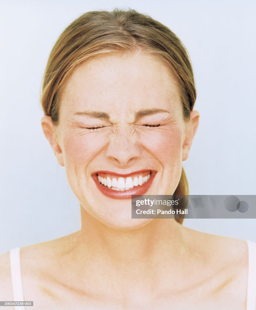 Young woman smiling, eyes closed, close-up