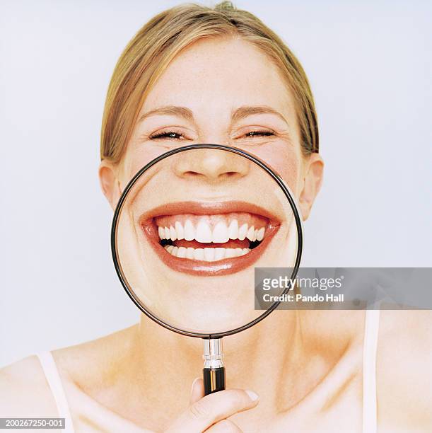 woman holding magnifying glass in front of mouth, smiling, portrait - offenes lächeln stock-fotos und bilder