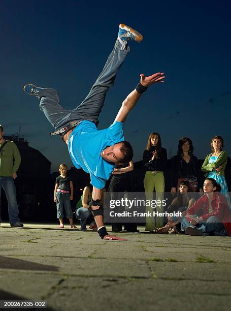 people watching young man break-dancing on street, night - breakdance stock pictures, royalty-free photos & images