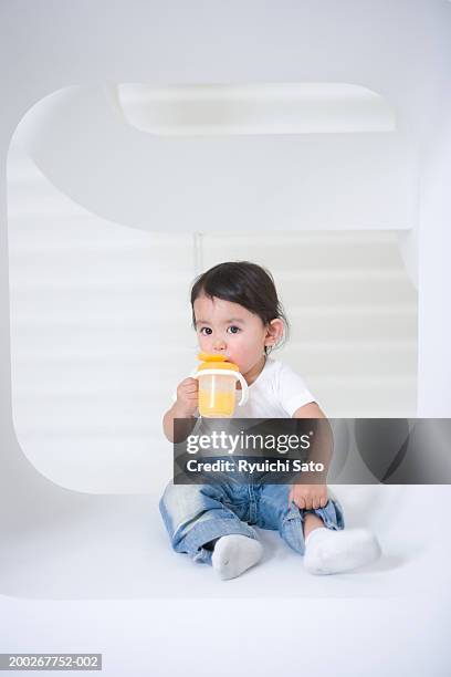 baby boy (18-21 months) sitting in recess, drinking from training cup - one baby boy only fotografías e imágenes de stock