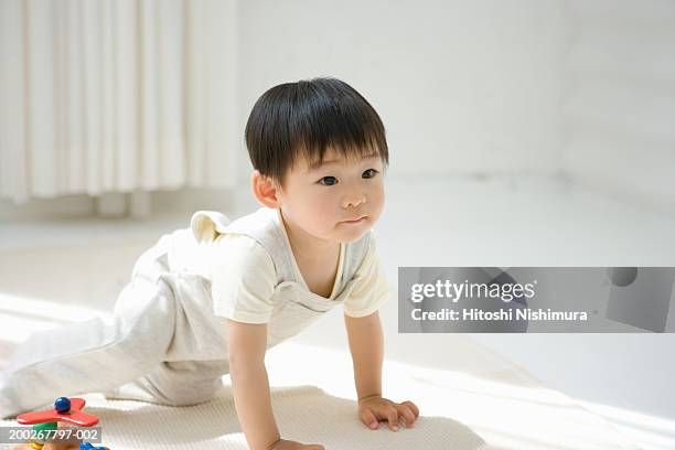 baby boy (18-21 months) kneeling on floor by toy - camminare a gattoni foto e immagini stock