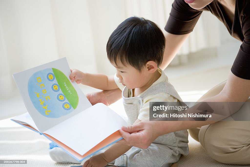 Mother and son (18-21 months) reading book, side view, close-up