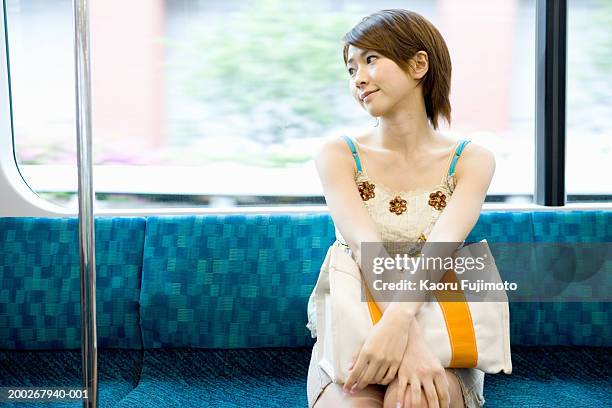 young woman sitting on train - 通勤電車 ストックフォトと画像