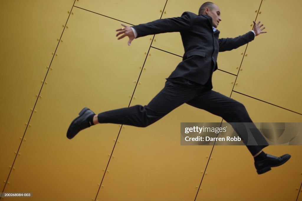 Young businessmen leaping, side view