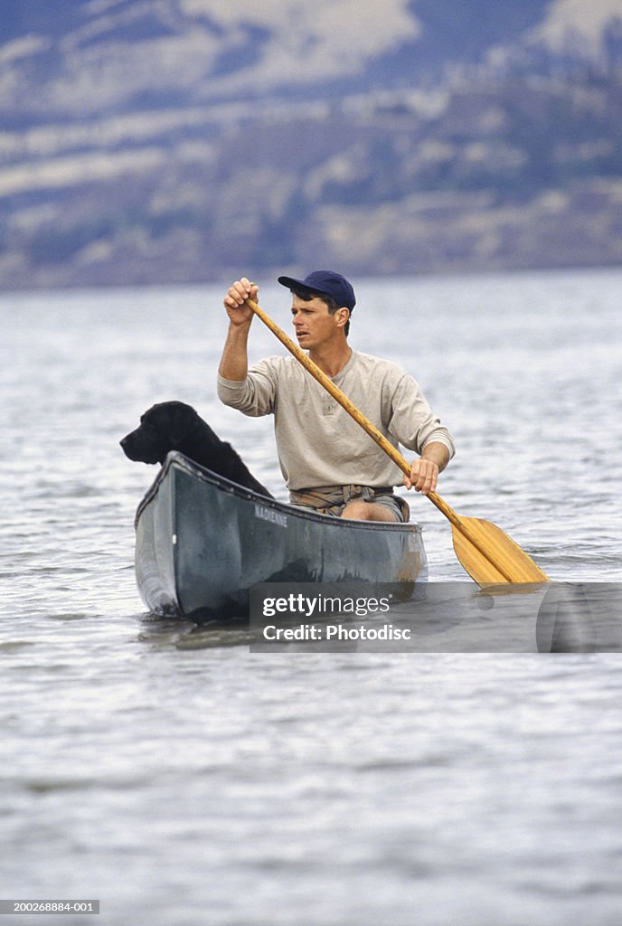 Man with dog canoeing on lake