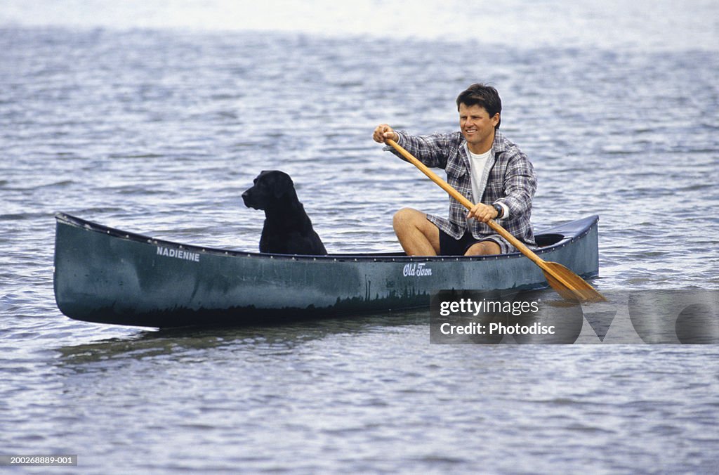 Man with dog canoeing on lake