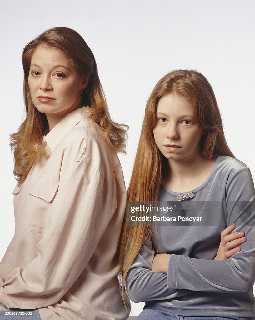 Mother sitting by frowning daughter (8-9), portrait