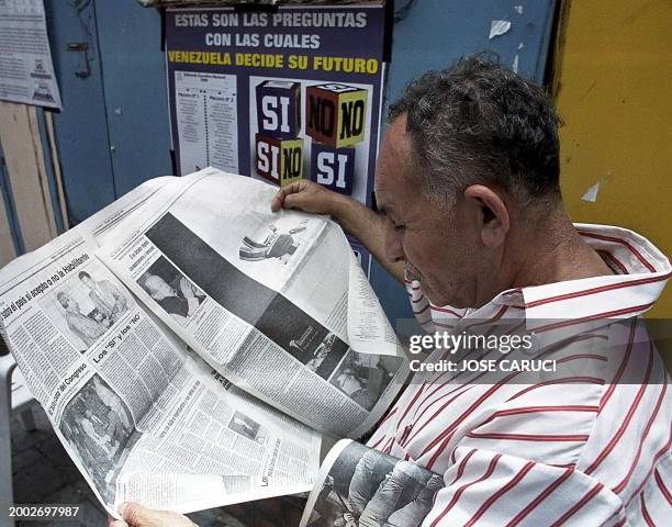 Un anciano lee el periodico frente a unos afiches del CNE pasa frente a unos afiches del MAS apoyando la participación al referendum constituyente...