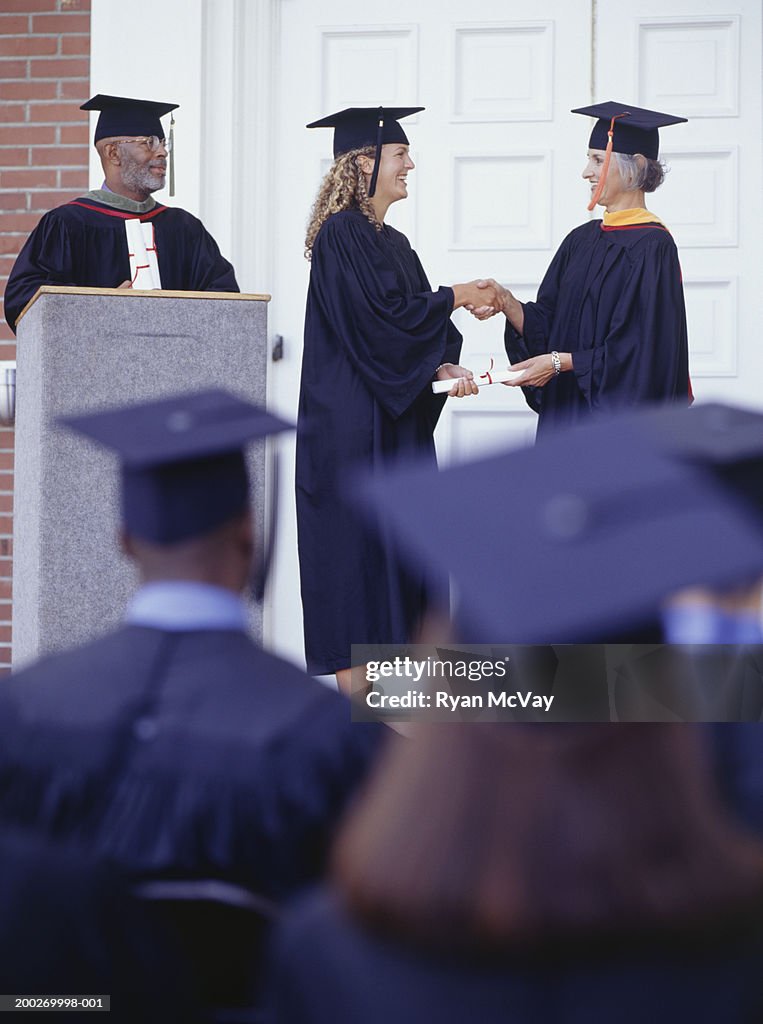 Graduate receiving diploma at graduation ceremony