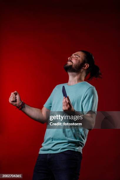 mann, der vor aufregung in die luft schlägt, wenn er ein level in einem videospiel gewinnt - faust in die luft stoßen stock-fotos und bilder