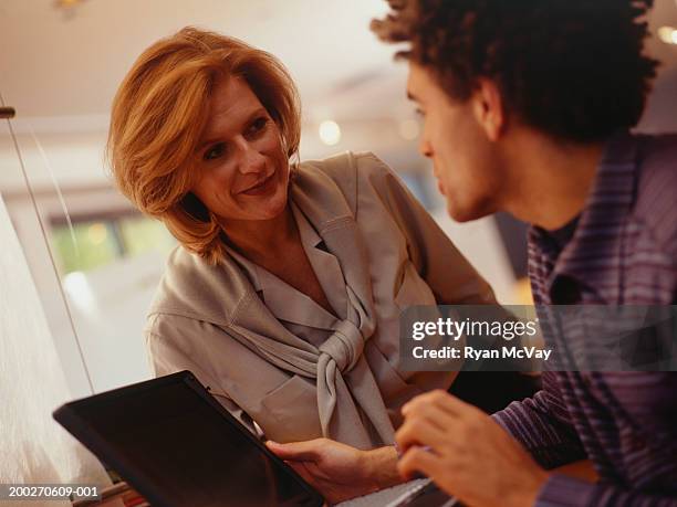 young man and woman in office, man holding laptop - purple shirt stock pictures, royalty-free photos & images