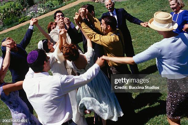 bride, groom and guests dancing at wedding in garden - jewish celebration stock pictures, royalty-free photos & images