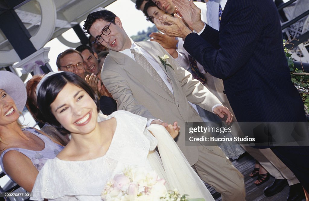 Group of guests applauding bride and groom at wedding ceremony