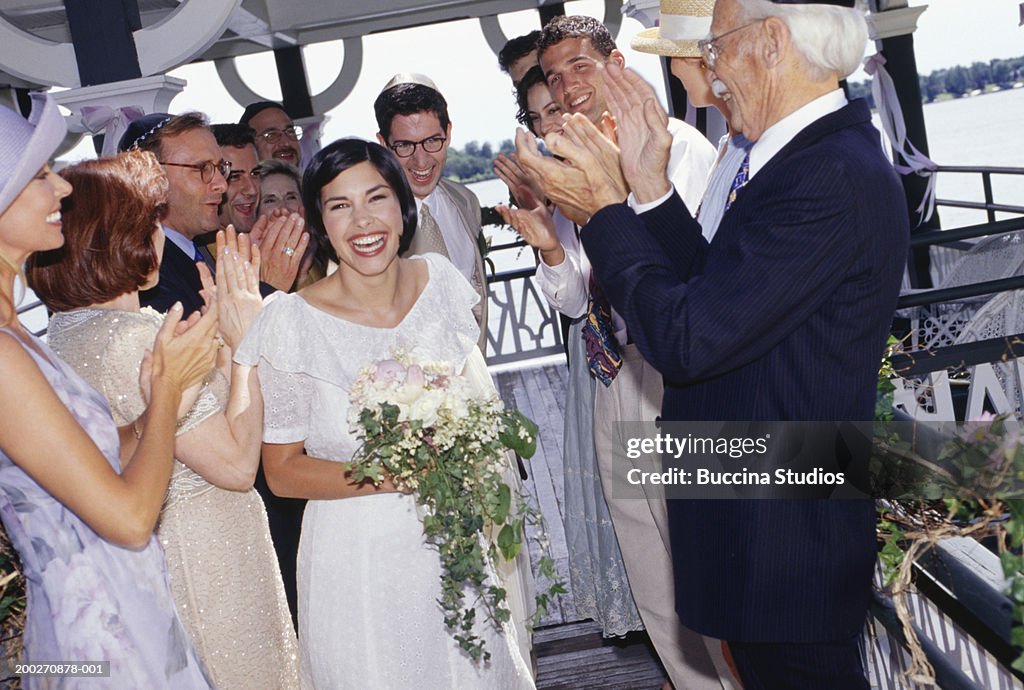 Group of guests applauding bride and groom at wedding ceremony