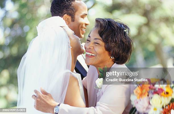 newly-wed couple standing in garden, bride embracing mother-in-law - mother and daughter smoking - fotografias e filmes do acervo