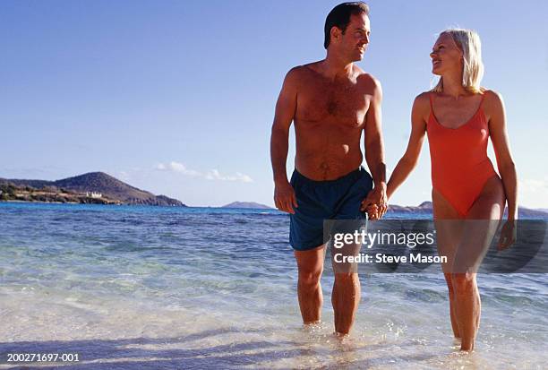 couple walking in surf, holding hands, low angle view - swimming costume stock pictures, royalty-free photos & images