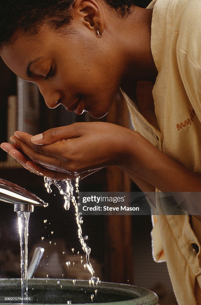 Woman washing face at sink in bathroom, close-up