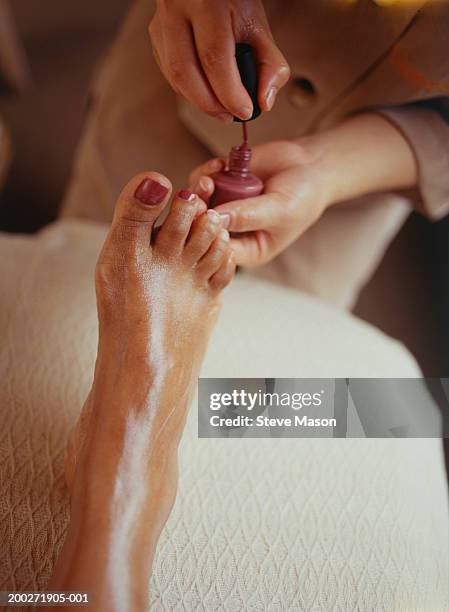woman varnishing toenails in beauty parlour, close-up, elevated view - pedicure foto e immagini stock