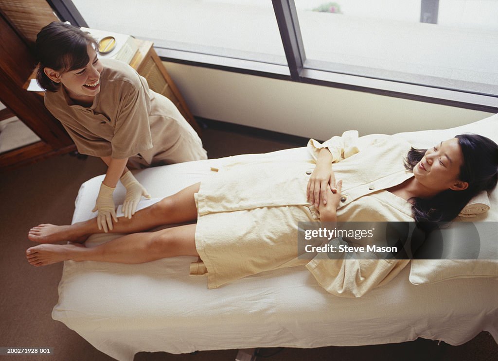 Woman lying on treatment table having leg wax