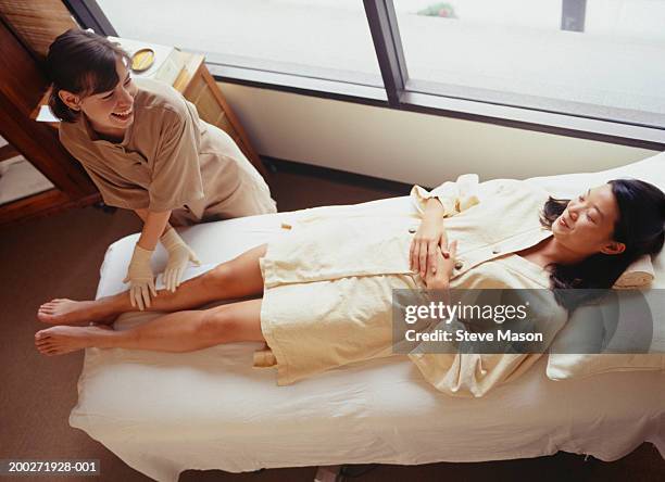 woman lying on treatment table having leg wax - wax figure stockfoto's en -beelden
