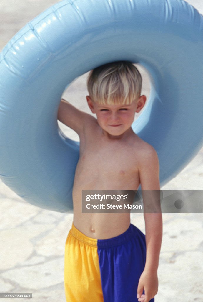 Boy (6-7) holding floating ring over head on beach