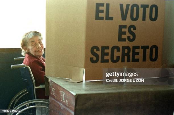 Una anciana en silla de ruedas ingresa 01 de febrero a la cabina para elegir a sus candidatos a presidente y diputados durante las elecciones...