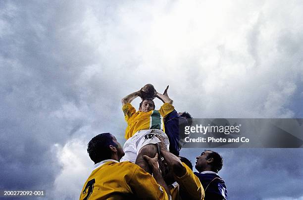rugby lineout jumper being supported by team-mates, low angle view - rugby sport stock-fotos und bilder