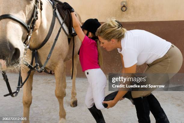 woman helping girl (4-6) onto horse - riding boots girl stock pictures, royalty-free photos & images