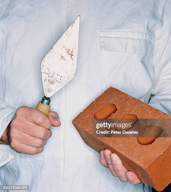 man holding trowel and brick, mid section, close-up - truelle photos et images de collection