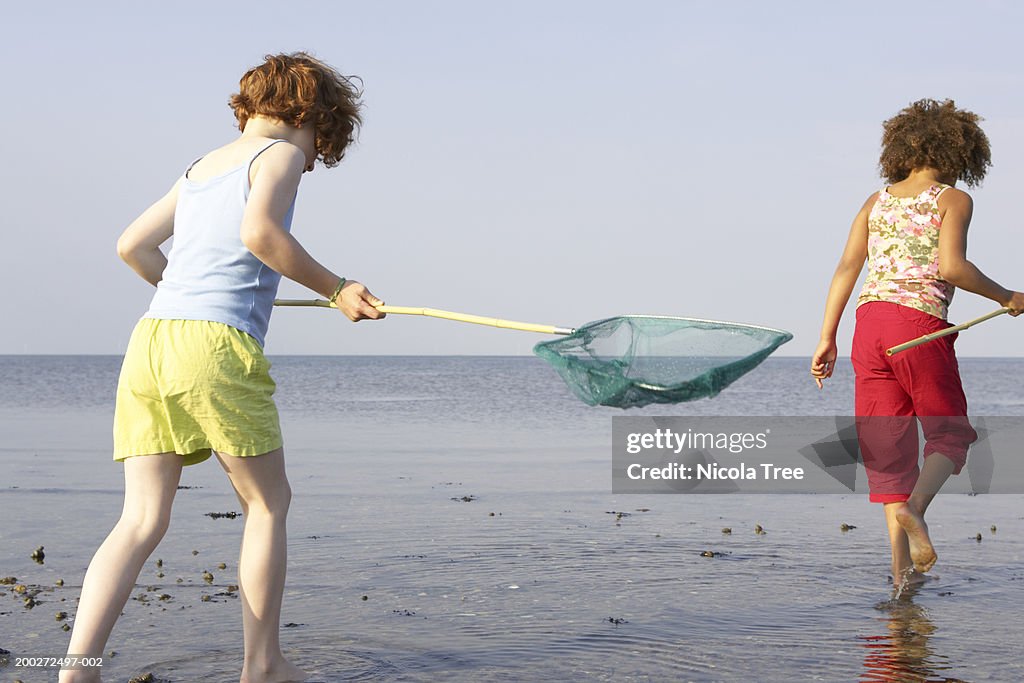 Two Girls Walking In Water Holding Fishing Nets High-Res Stock