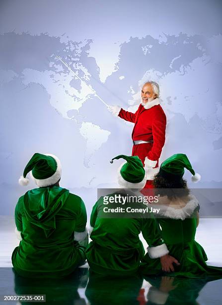 'santa' showing three 'elves' world map (digital composite) - naughty santa stock pictures, royalty-free photos & images