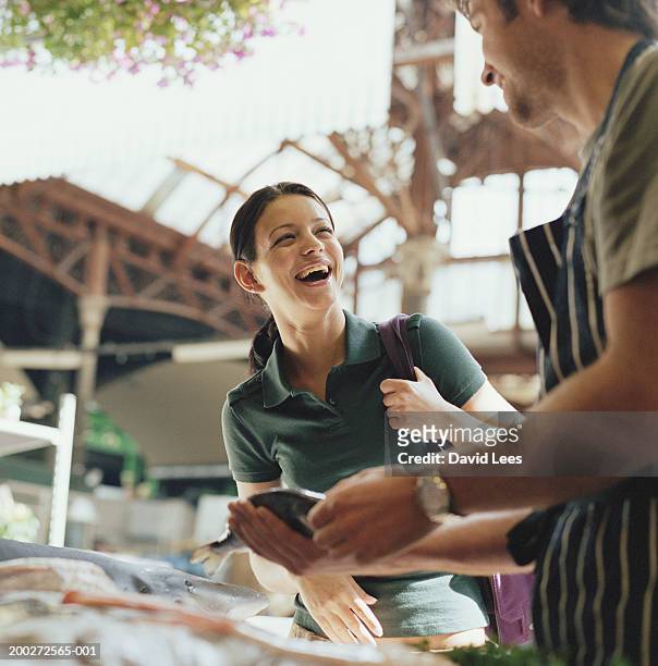 woman buying fish from fishmonger in market, smiling (focus on woman) - fish vendor bildbanksfoton och bilder