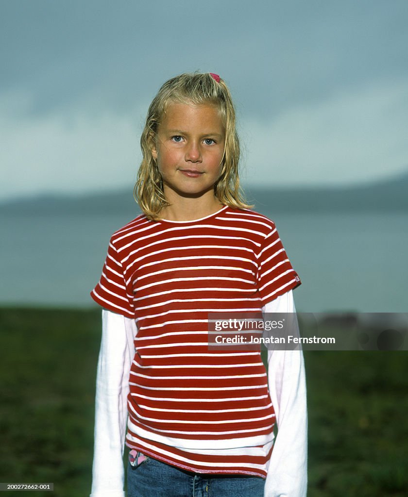Girl (7-9) standing coastal landscape, portrait (focus on girl)
