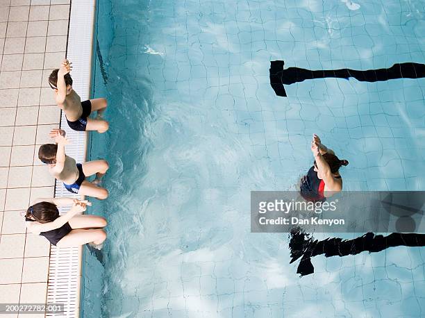 swimming coach teaching children (8-10) on poolside to dive - leren zwemmen stockfoto's en -beelden