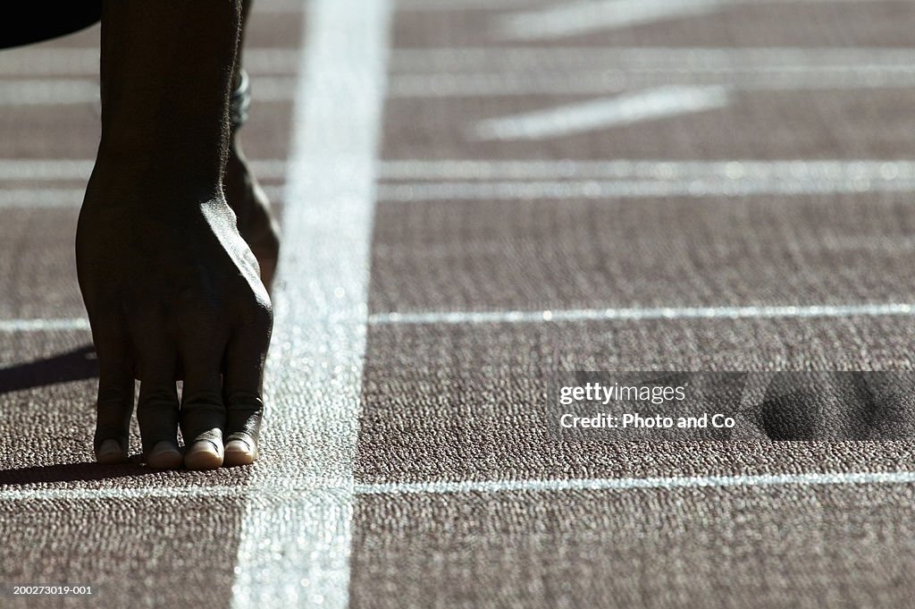 Man in starting position on running track, close-up
