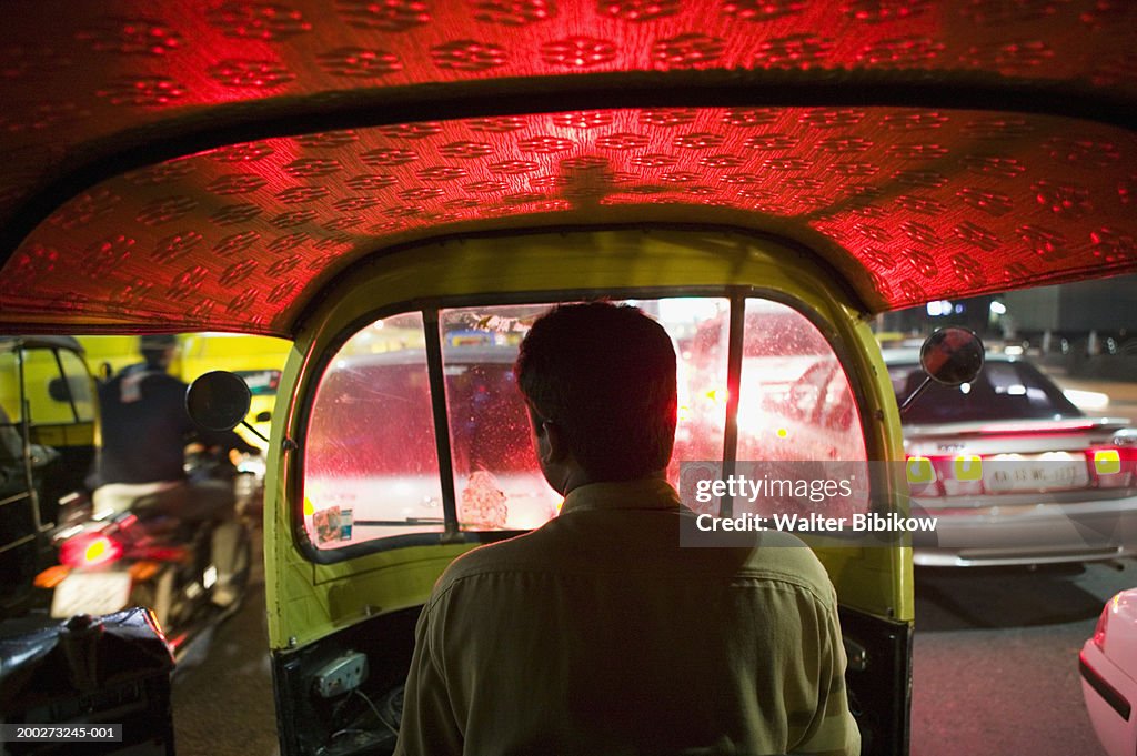 Autorickshaw taxi driving in evening traffic, rear view