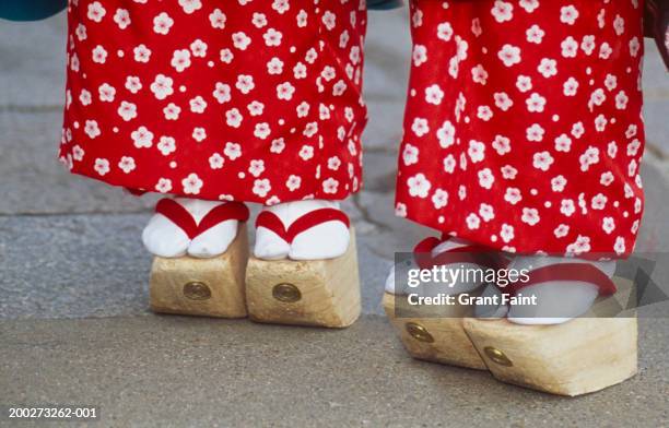 two women wearing traditional japanese "geta" slippers, low section - geta sandal stock-fotos und bilder