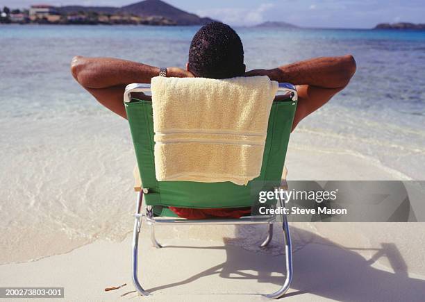 man sunbathing in deckchair at ocean, rear view - man on the beach relaxing in deckchair fotografías e imágenes de stock