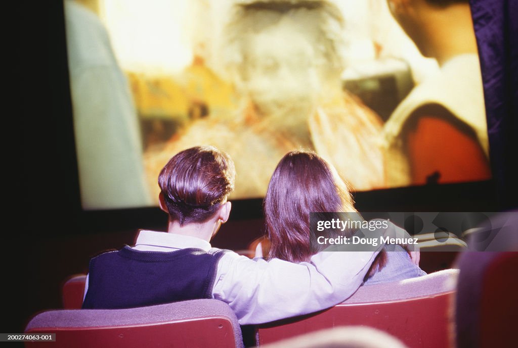 Teenage couple (16-17) sitting in cinema, watching movie