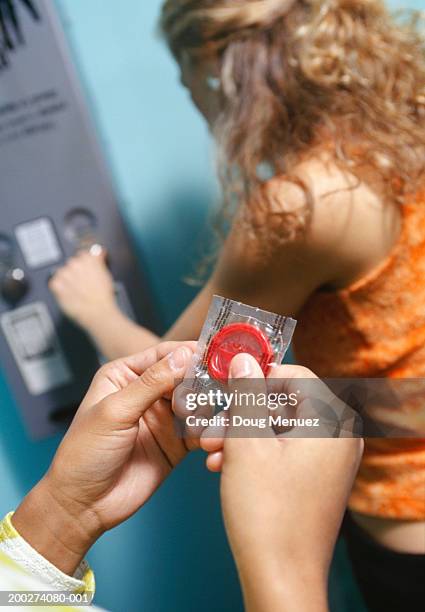 young woman buying condoms from vending machine, person holding condom in hands - condom bildbanksfoton och bilder