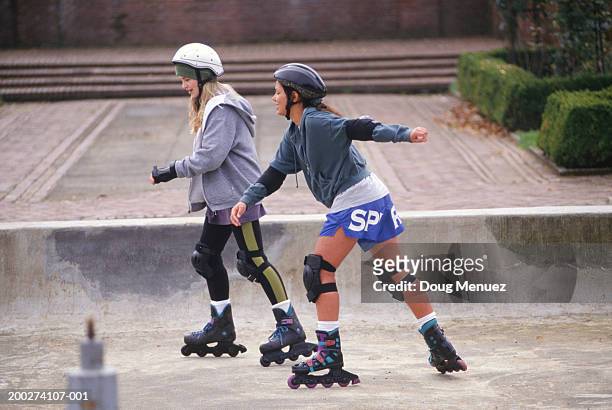 two teenage girls (14-15) inline skating in park - girl roller skates stock pictures, royalty-free photos & images