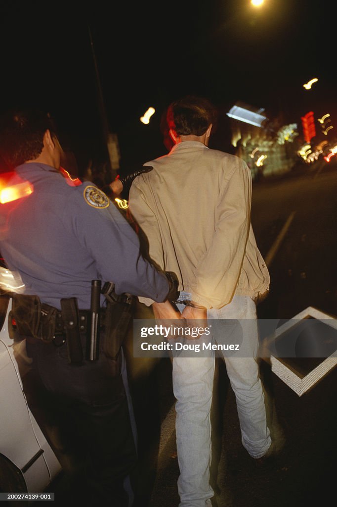 Teenage boy (16-17) being arrested, rear view