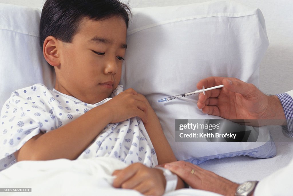 Doctor in hospital giving boy (5-6) injection in arm