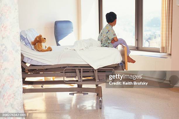young boy (6-7) sitting on hospital bed - children's hospital imagens e fotografias de stock